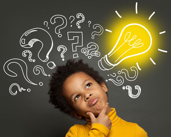 A little boy just learned something as a light bulb illuminates near his head among many question marks.